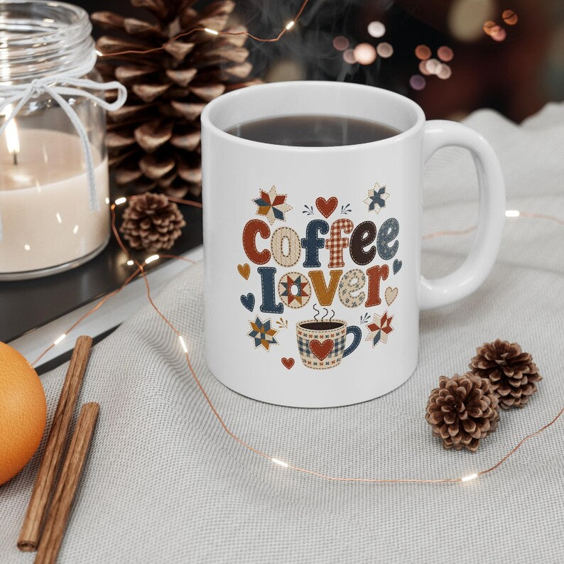 White handled mug with patterned Coffee Lover lettering, hearts, quilt-style stars, and a coffee cup illustration.