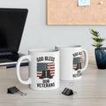Two white handled mugs displaying God Bless Our Veterans lettering, an American flag, and boots. Listing includes one mug.