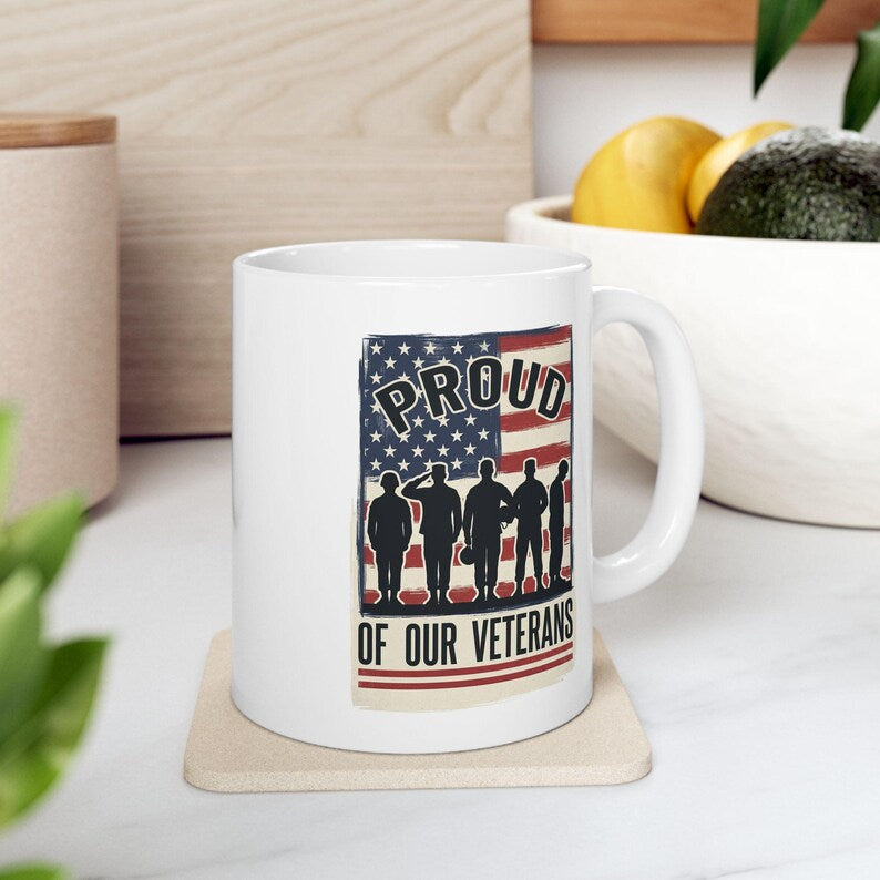 White handled mug with an American flag, service member silhouettes, and Proud of Our Veterans lettering.