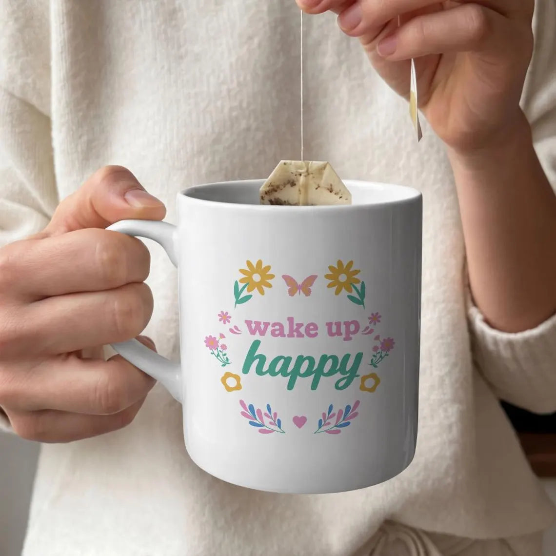 White handled mug with Wake Up Happy lettering, pastel flowers, a butterfly, and a pink heart.