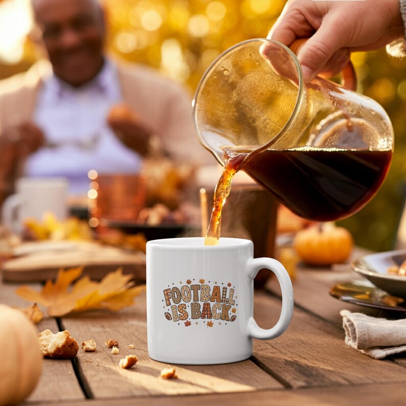 White handled Football Is Back mug on an autumn table as coffee is poured into it.